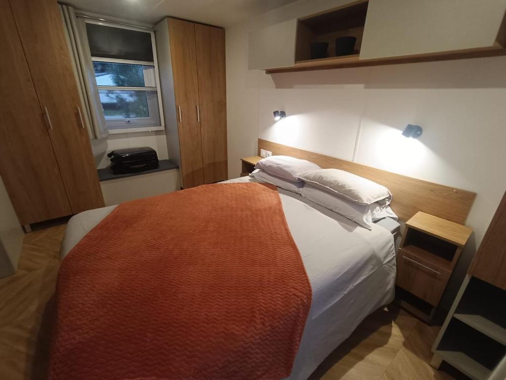 une chambre avec un lit avec des draps blancs et des oreillers dans l'établissement Mobile home Grand confort, à Lège-Cap-Ferret