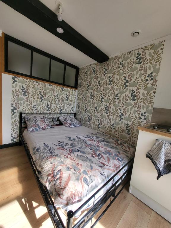 - une chambre avec un lit dans une pièce avec du papier peint dans l'établissement Studio Equipé La Glacerie, à Cherbourg en Cotentin