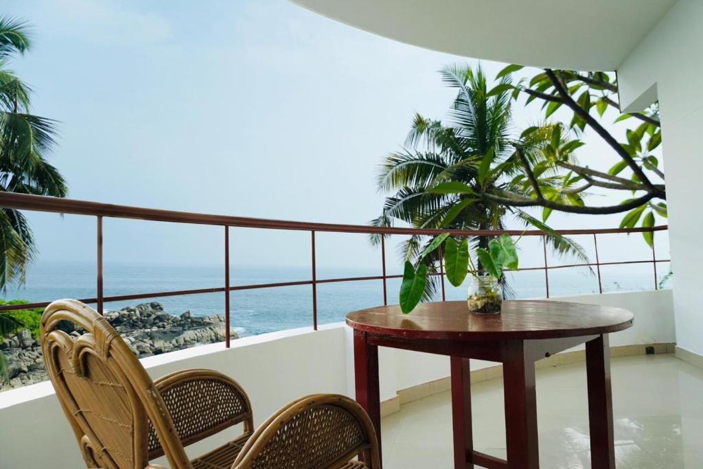 a balcony with a table and chairs and the ocean at Udaya Hotel in Kovalam