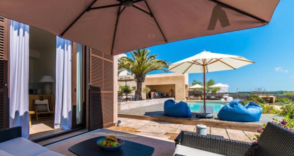 an outdoor patio with an umbrella and a pool at Apartamento Villa Cabrera in Colònia De Sant Jordi