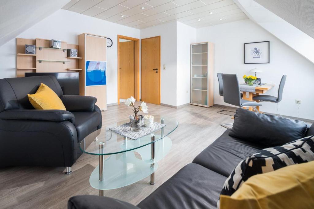 a living room with two couches and a glass table at Mayglück App 3 in Norderney