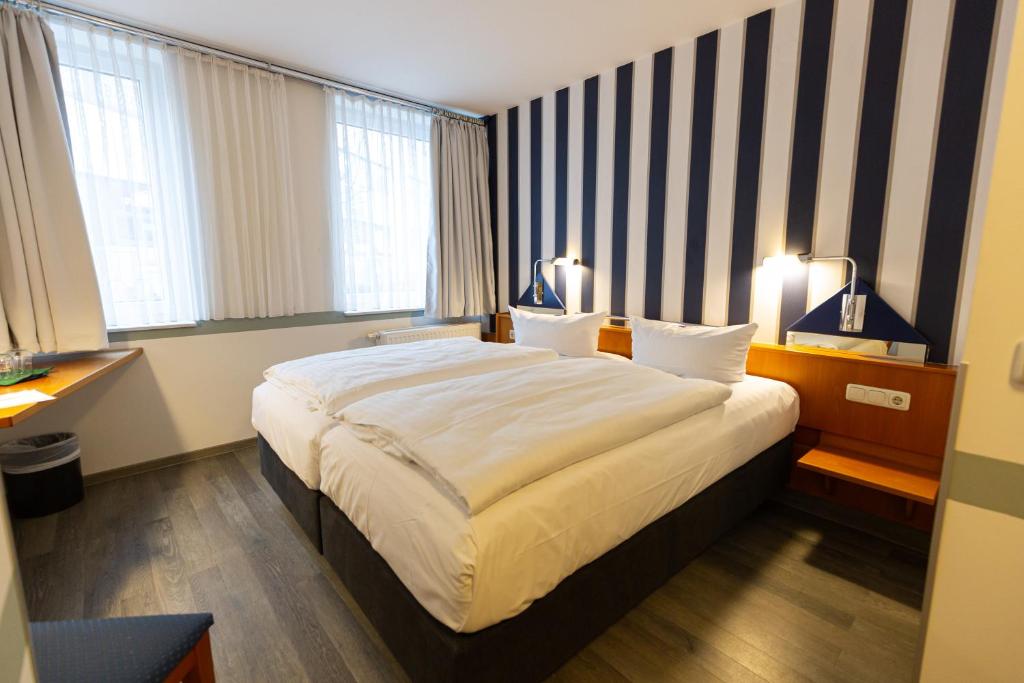 a hotel room with a large bed and two windows at Hotel DH VEC, sehr beliebtes & leckeres Frühstück, Self-Check-In in Vechta