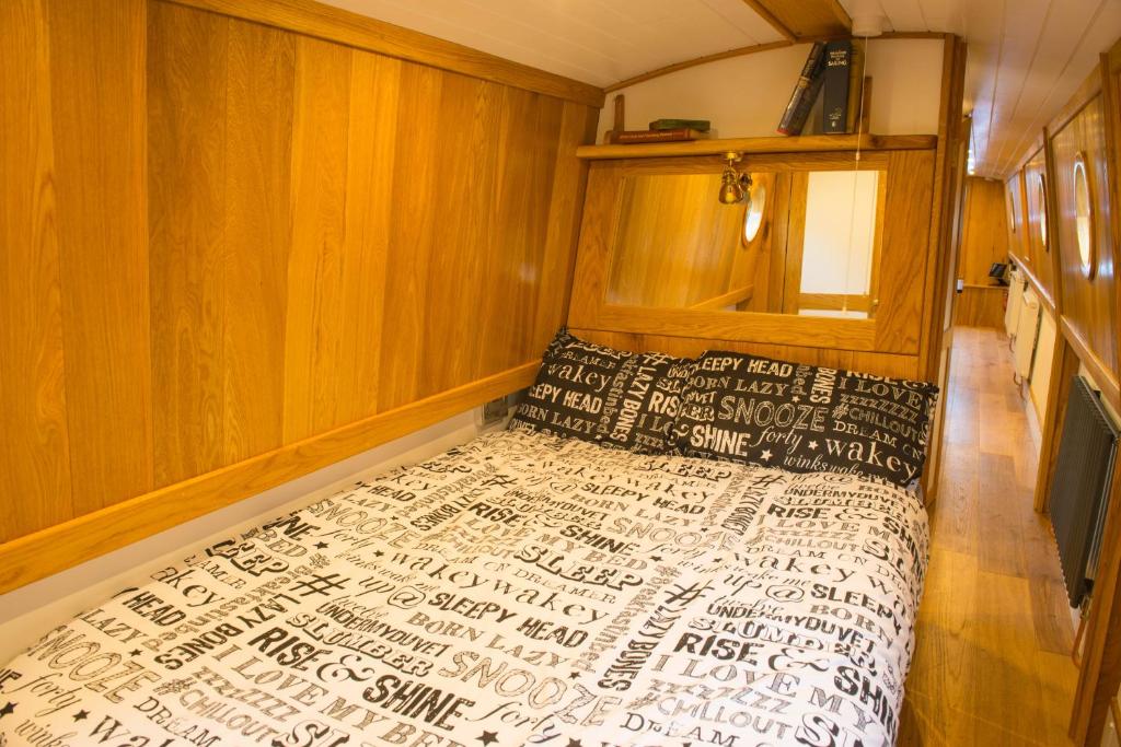 a bedroom with a bed and wooden walls at Narrowboat Puzzle in Ely