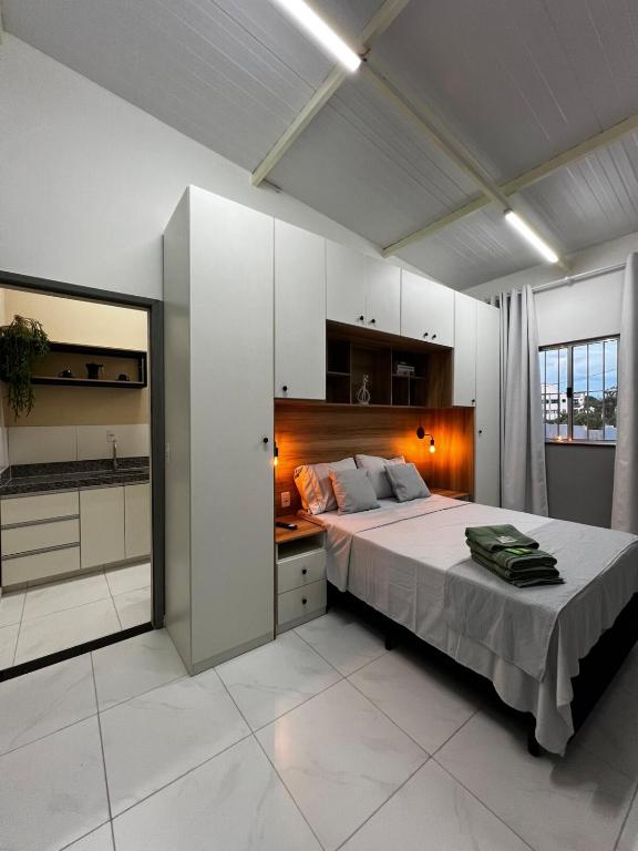 a large white bedroom with a bed and a kitchen at Loft Oriente - 800m do Parque das Águas in São Lourenço