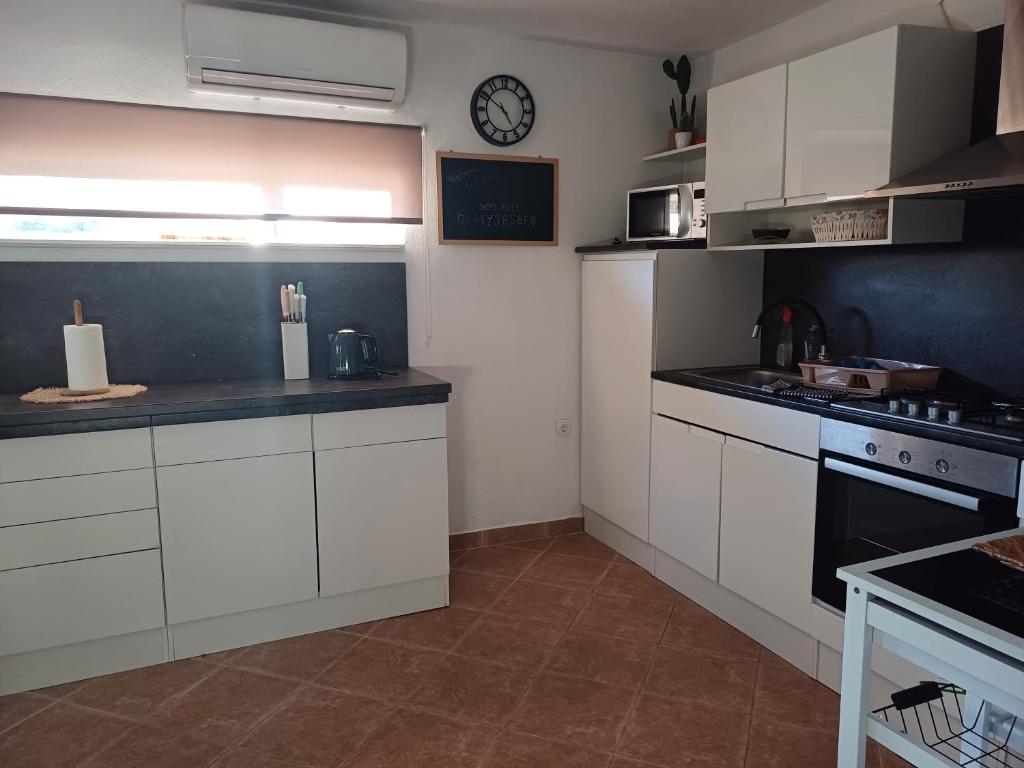 kuchnia z białymi szafkami i zegarem na ścianie w obiekcie Holiday House Pulina w mieście Punat