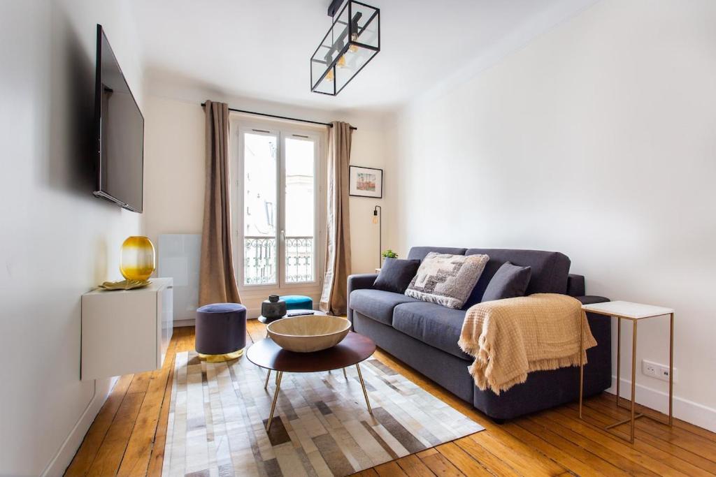 un salon avec un canapé bleu et une table dans l'établissement Montmartre Seveste Beautiful Apartment 2BR, à Paris