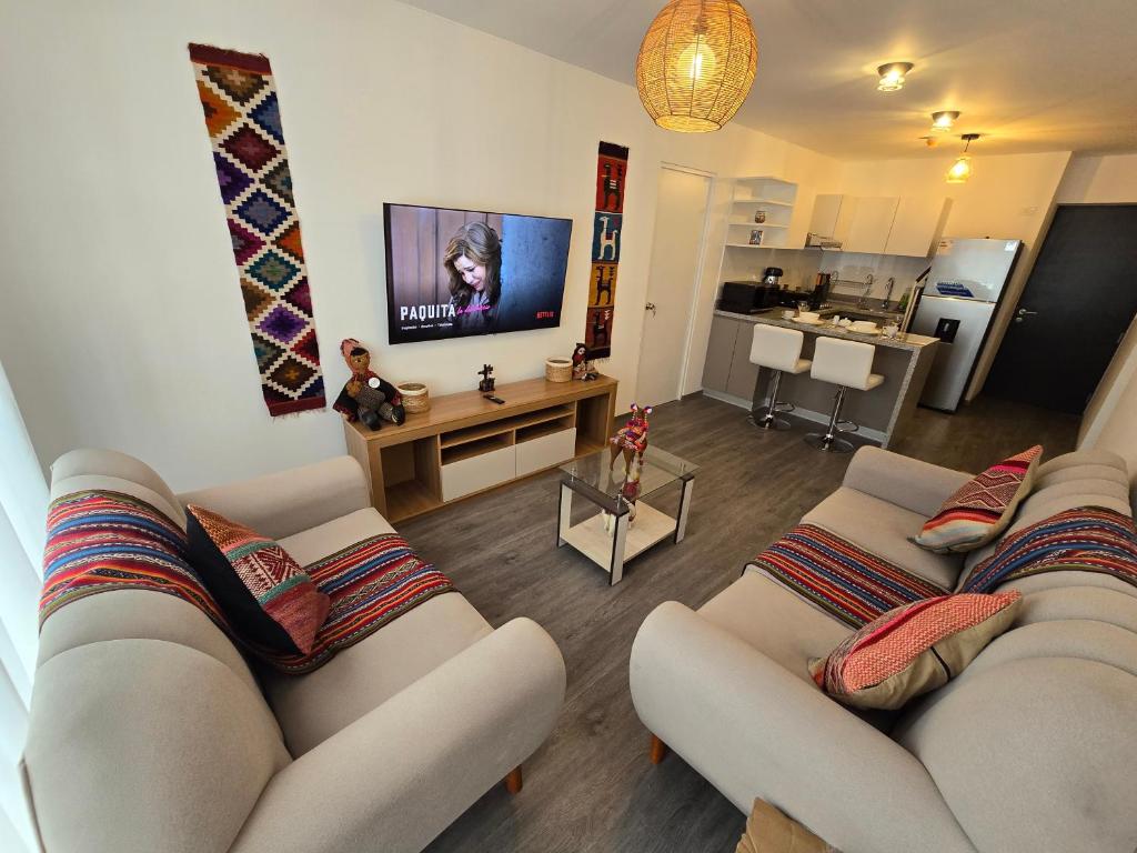 a living room with two couches and a flat screen tv at Acogedor Departamento en Cusco, Ideal para Familias y Amigos, Equipado y Céntrico in Cusco