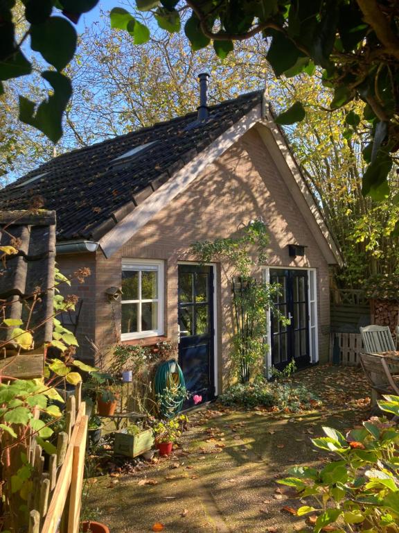 a small brick house with a door and a fence at Pluk het Geluk in Laag-Soeren