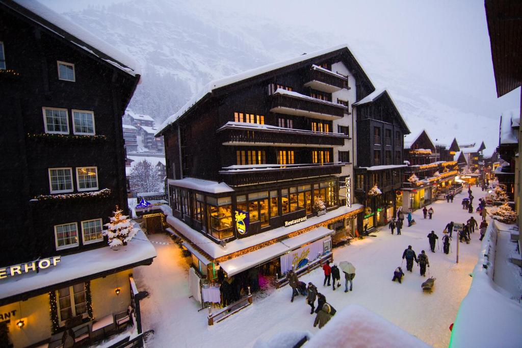 a group of people walking down a street with buildings at Hotel Pollux in Zermatt