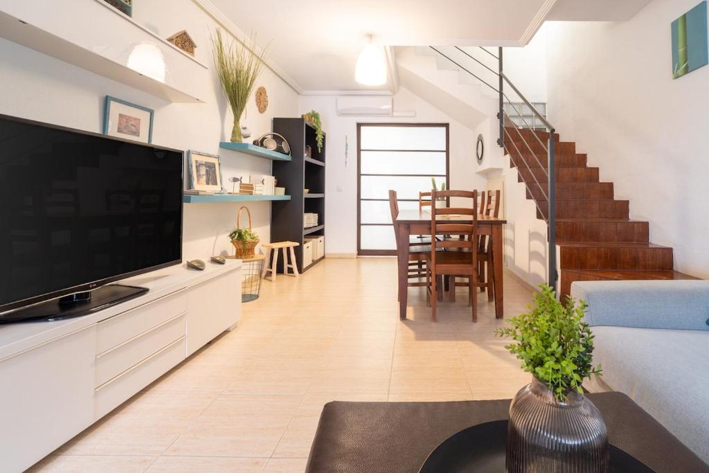 a living room with a television and a living room with a staircase at Chalet adosado en la playa de Torre de la Horadada in Torre de la Horadada
