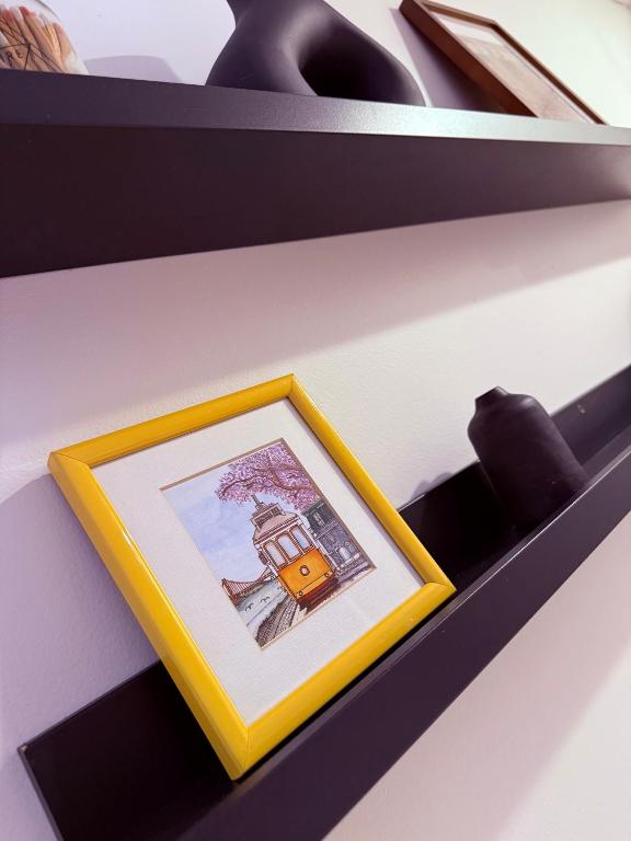 a picture in a yellow box on a shelf at le plateau suite in Queens