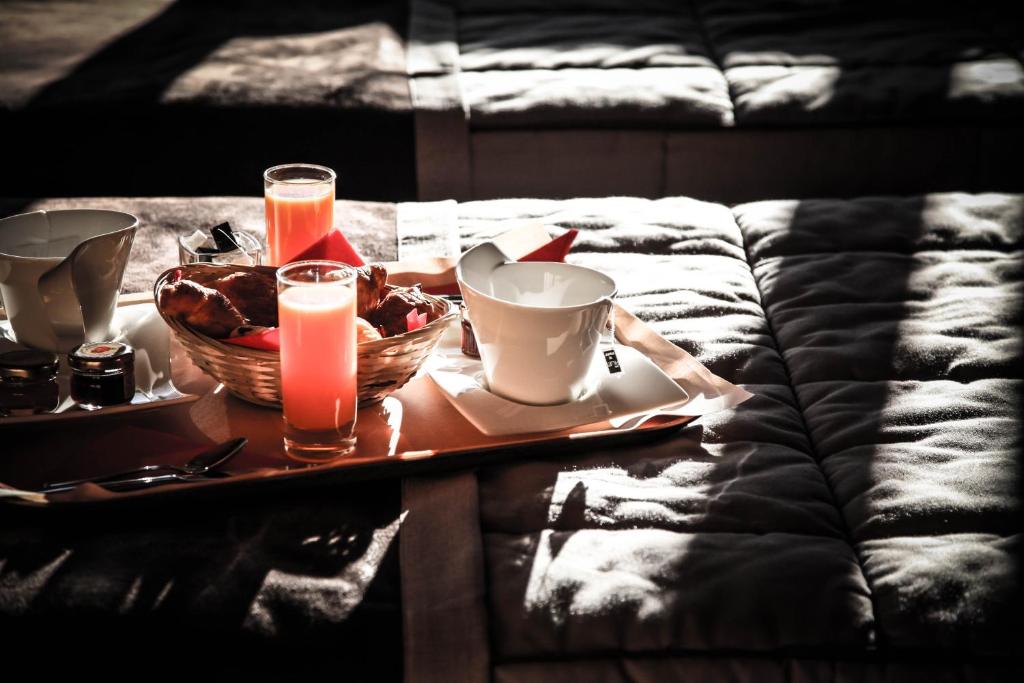 a tray with food and drinks on a bed at Hôtel Le Refuge in Tignes