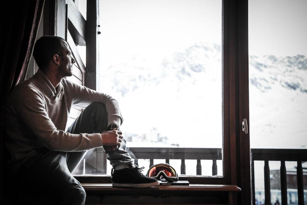 a man sitting on a window sill with his shoes on at Hôtel Le Refuge in Tignes