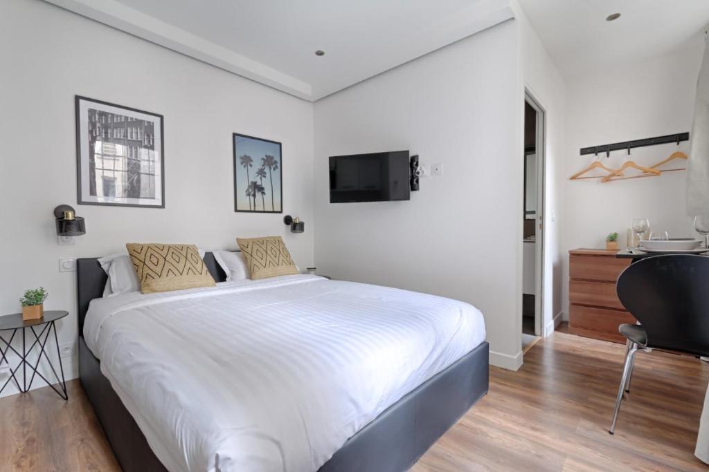 une chambre avec un grand lit blanc et un bureau dans l'établissement TBS 308 - Beautiful studio near Marais district, à Paris