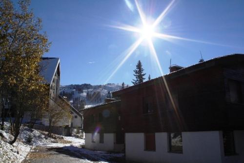 a sun shining over a building with snow on the ground at Apartman Kosuta B3 in Jahorina