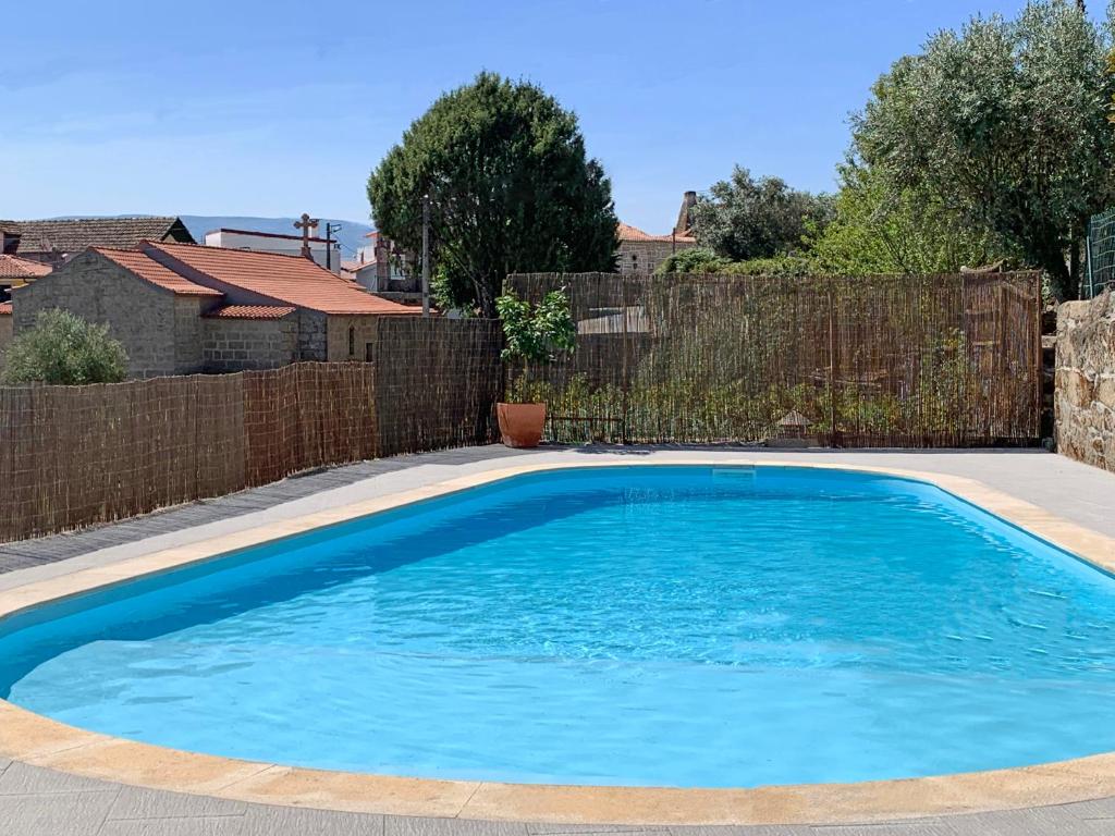 a large blue swimming pool in front of a fence at Casa da Regadinha in Muxagata