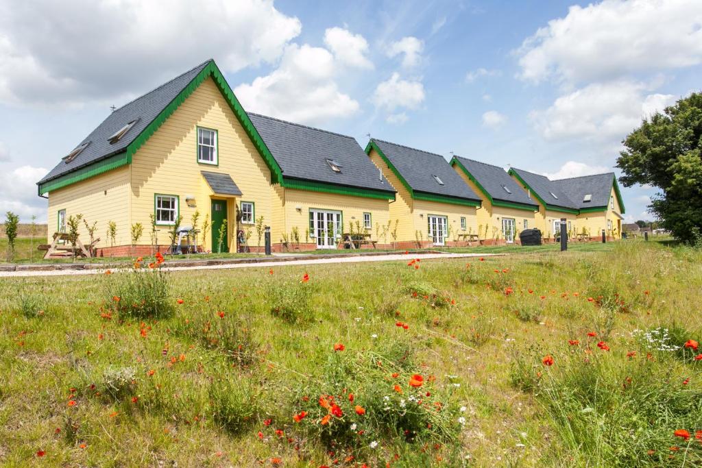 a large yellow house with a field of flowers at Watercress Lodges & Campsite in New Alresford