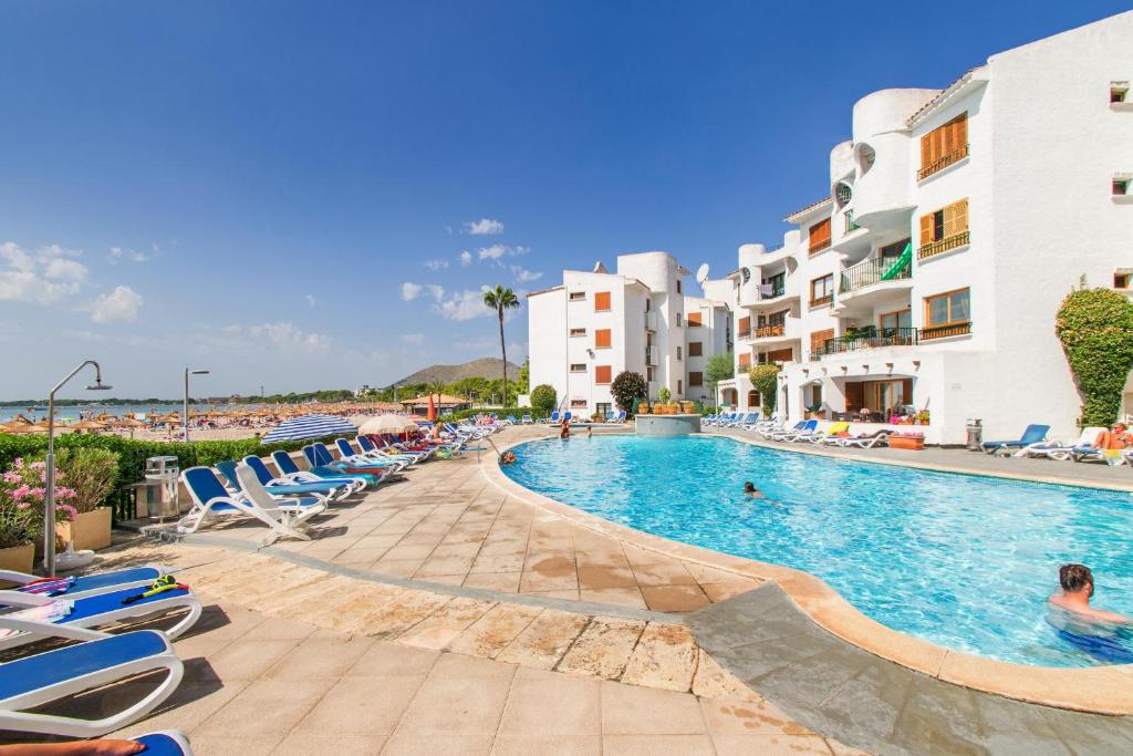 a pool at a resort with lounge chairs and buildings at Carabela in Port d'Alcudia
