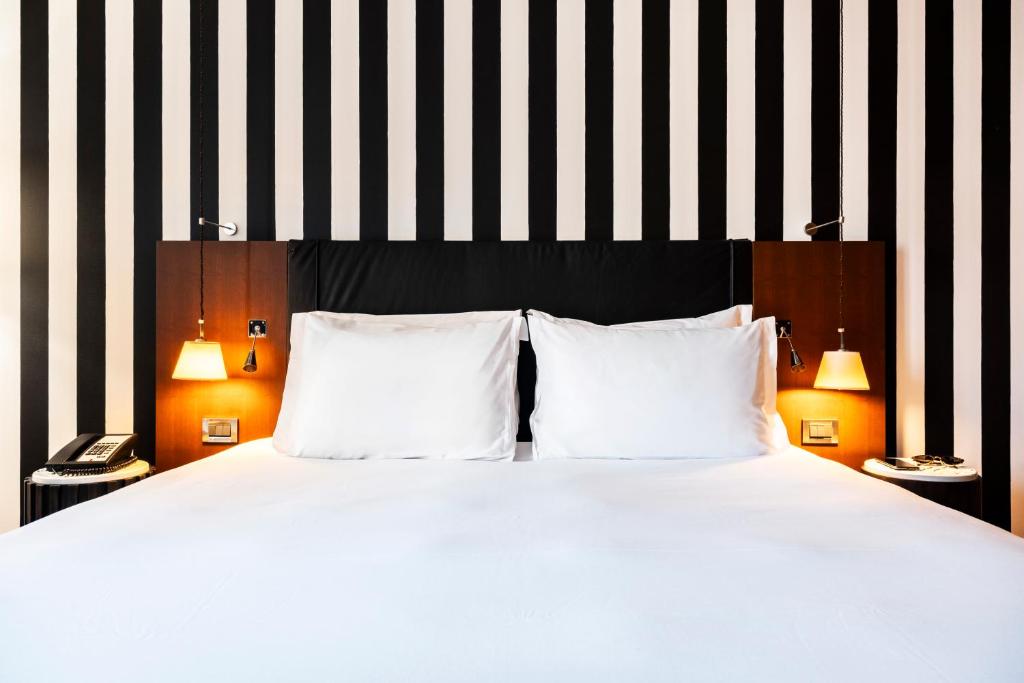 a bed with two white pillows and a black and white striped wall at Grand Hôtel Champs-Elysées in Paris
