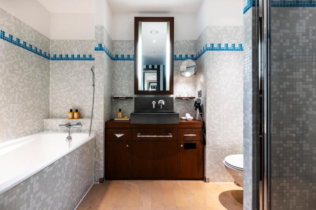 a bathroom with a tub and a sink and a mirror at Grand Hôtel Champs-Elysées in Paris