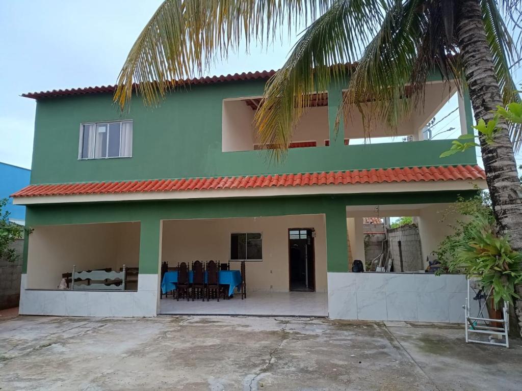 a green and white house with a palm tree at Casa Duplex Gramuté - Praia Grande - ES in Fundão