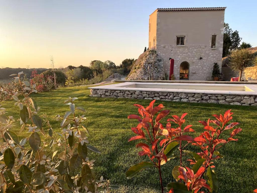 un bâtiment avec une cour ornée de fleurs rouges devant elle dans l'établissement La Maison de Léo, à Saint-Mitre-les-Remparts