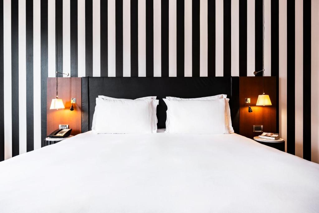 a bedroom with a large white bed with black and white stripes at Grand Hôtel Champs-Elysées in Paris