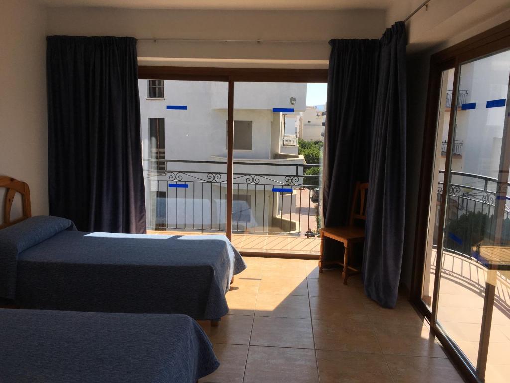 a bedroom with two beds and a balcony at Hostal Residencia Nicolau in San Antonio