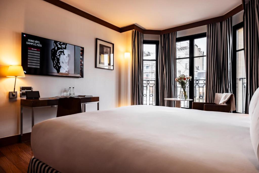 a hotel room with a large bed and a desk at Grand Hôtel Champs-Elysées in Paris