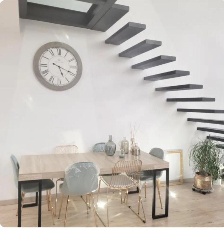 une salle à manger avec une table et une horloge au mur dans l'établissement Magnifique Villa piscine jacuzzi privé, à Saint-Féliu-dʼAvall