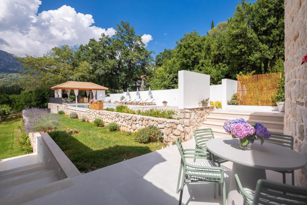 a patio with a table and chairs and a stone wall at Villa Emelie in Dubravka