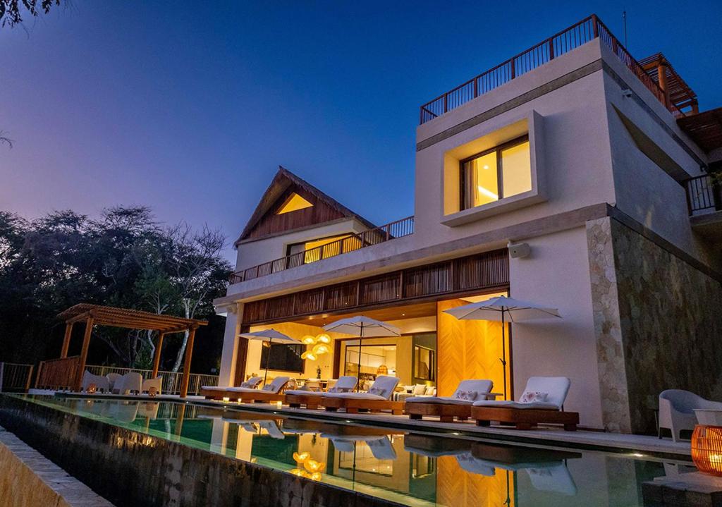 a house with a swimming pool in front of it at Casa Coral, Luxury Beachfront in Higuera Blanca