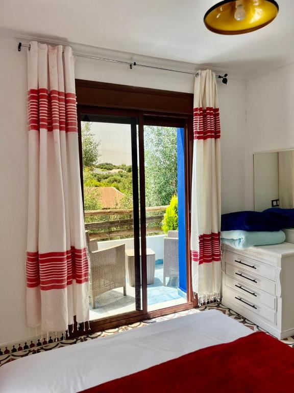 a bedroom with a bed and a large window at Dmina House in Asilah