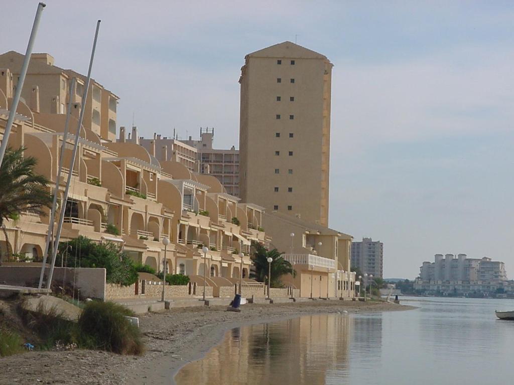 un edificio en una playa junto a un cuerpo de agua en Apartamentos Neptuno GL V.v., en La Manga del Mar Menor