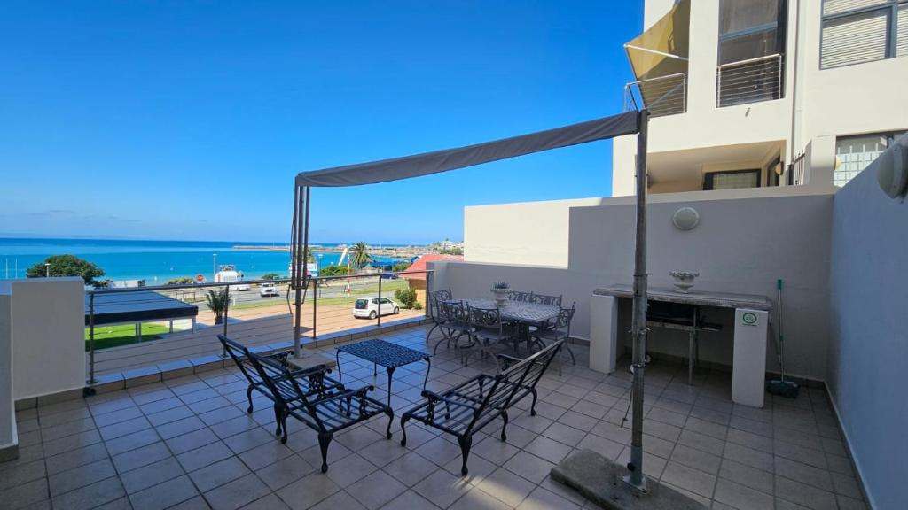 a balcony with tables and chairs and a view of the ocean at Santos 24 in Mossel Bay
