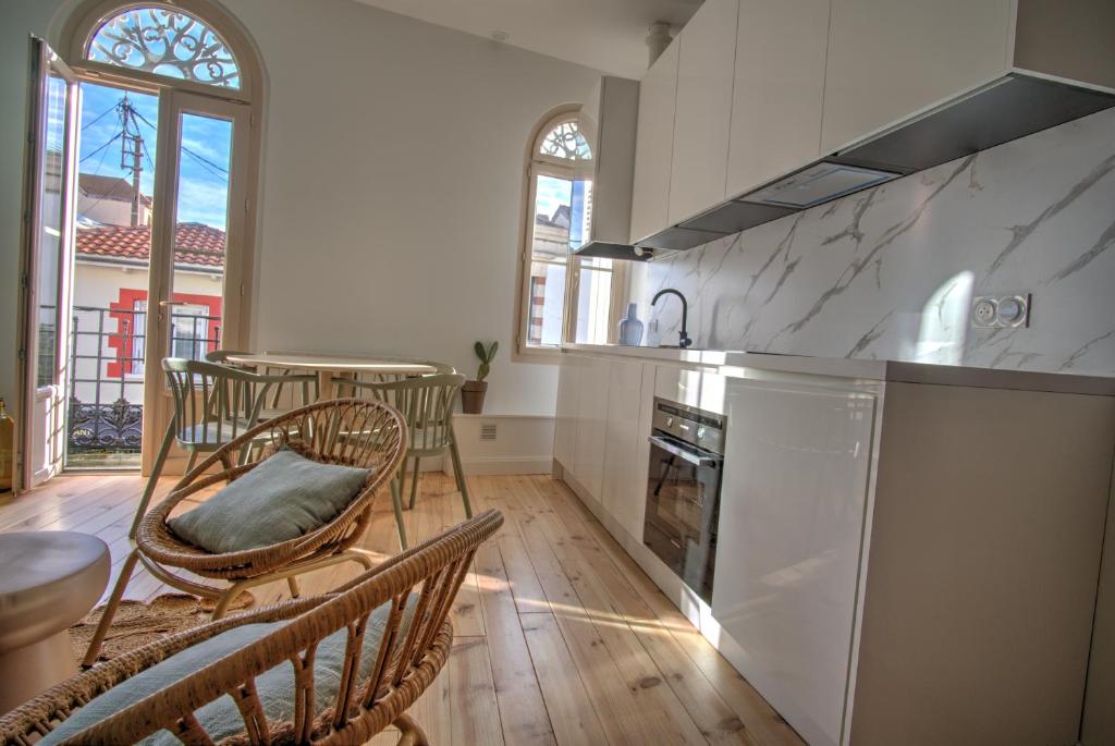 une cuisine avec des chaises, une table et un comptoir dans l'établissement Petit cocon en cœur de ville, à Arcachon