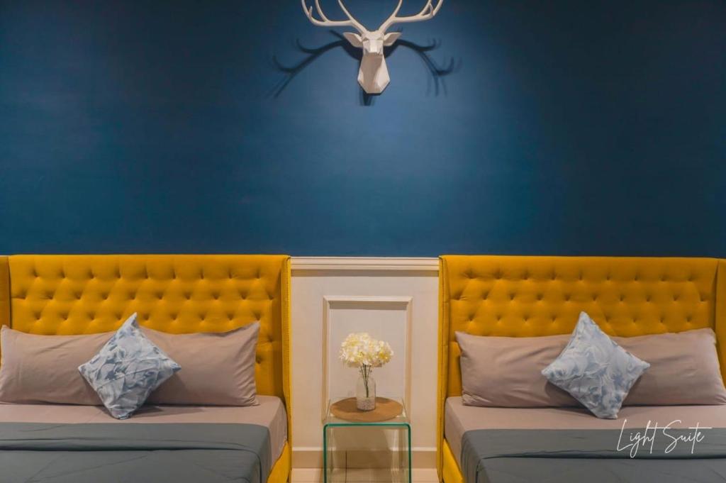 two beds in a room with a blue wall at Cozy Room 5min From Airport Wi-fi & Netflix At Aeropod Sovo in Kota Kinabalu