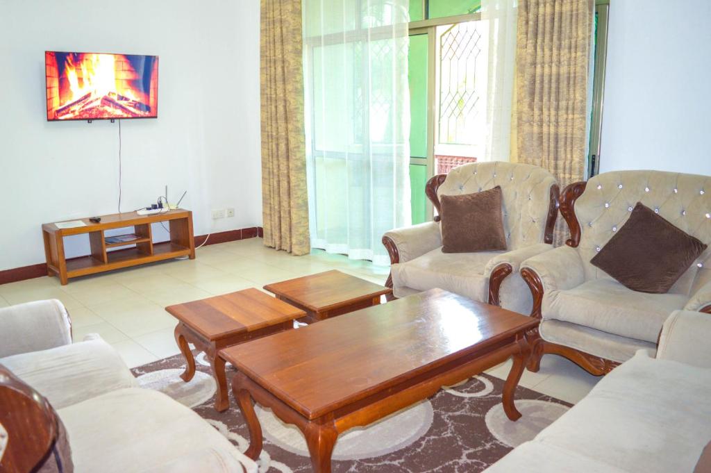 Roma Stays - Cozy 3 Bedroom Apartment with Swimming Pool in Shanzu في مومباسا: غرفة معيشة مع طاولة قهوة وكراسي