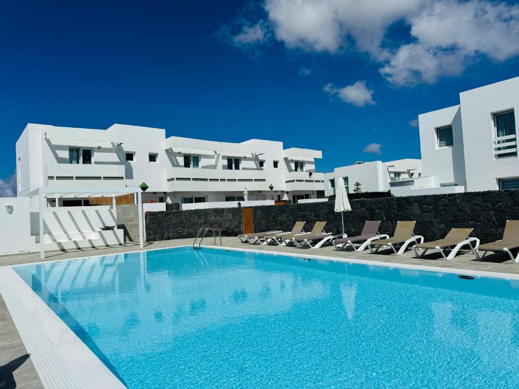a swimming pool in front of a large white building at Casa Noa by Vulcano Homes in Costa Teguise