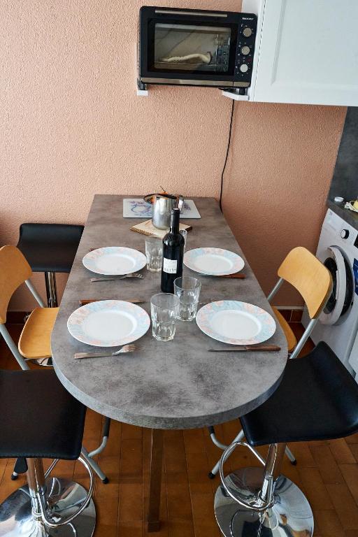 - une table avec des assiettes, des verres et une bouteille de vin dans l'établissement Cocon calme proche de la mer, au Cap d'Agde