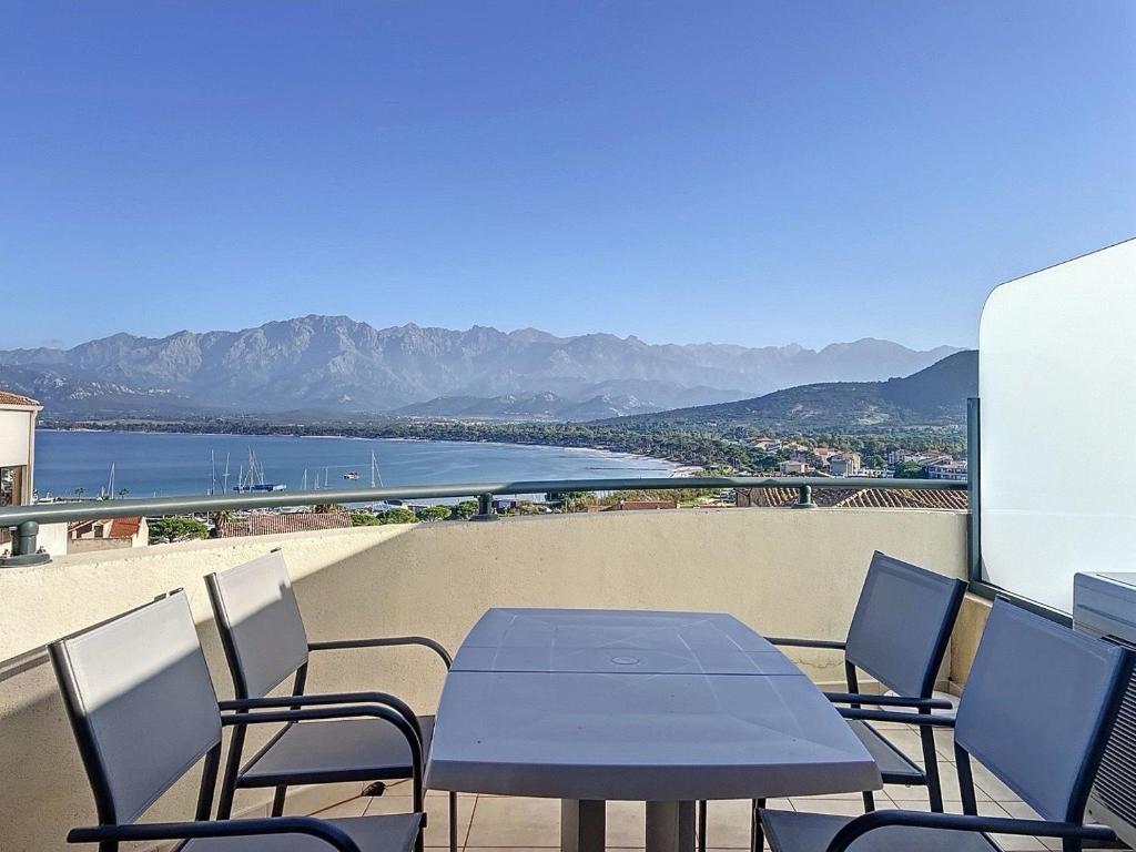 ein Tisch und Stühle auf einem Balkon mit Blick auf das Wasser in der Unterkunft Bel appartement vue mer-montagne in Calvi