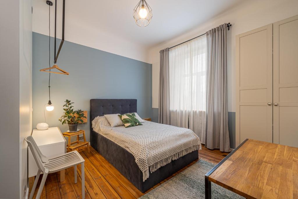 a bedroom with a bed and a table and a chair at Baltic Design Apartments with free Parking and self check in in Rīga