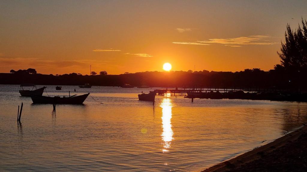 a sunset over a river with boats in the water at Egidios AP - Centro de São Pedro da Aldeia in São Pedro da Aldeia