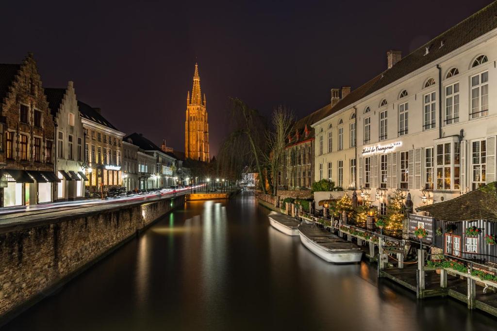 a clock tower towering over a city at night at Hotel De Orangerie - Small Luxury Hotels of the World in Bruges