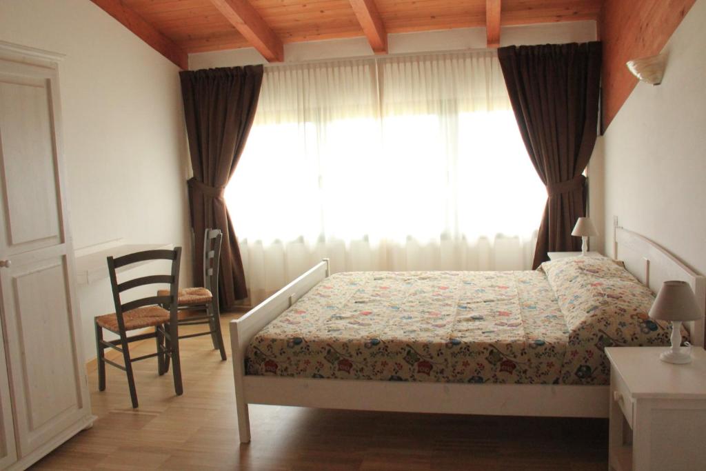オッツァーノ・デッレミーリアにあるLa Palazzina di Ciagnanoのベッドルーム1室(ベッド1台、椅子、窓付)