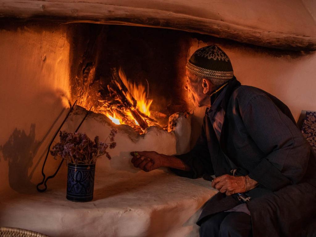 a man sitting in front of a fireplace at Hotel-Restaurant Le Kaouki in Sidi Kaouki