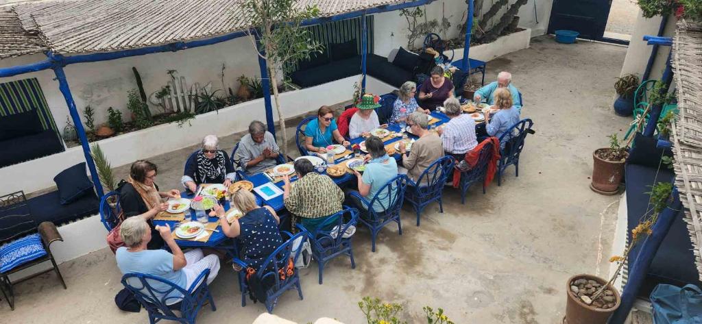 a group of people sitting at a table eating at Hotel-Restaurant Le Kaouki in Sidi Kaouki