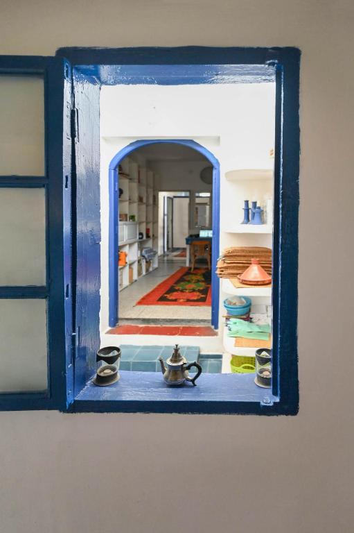 a blue window with a view of a room at Hotel-Restaurant Le Kaouki in Sidi Kaouki