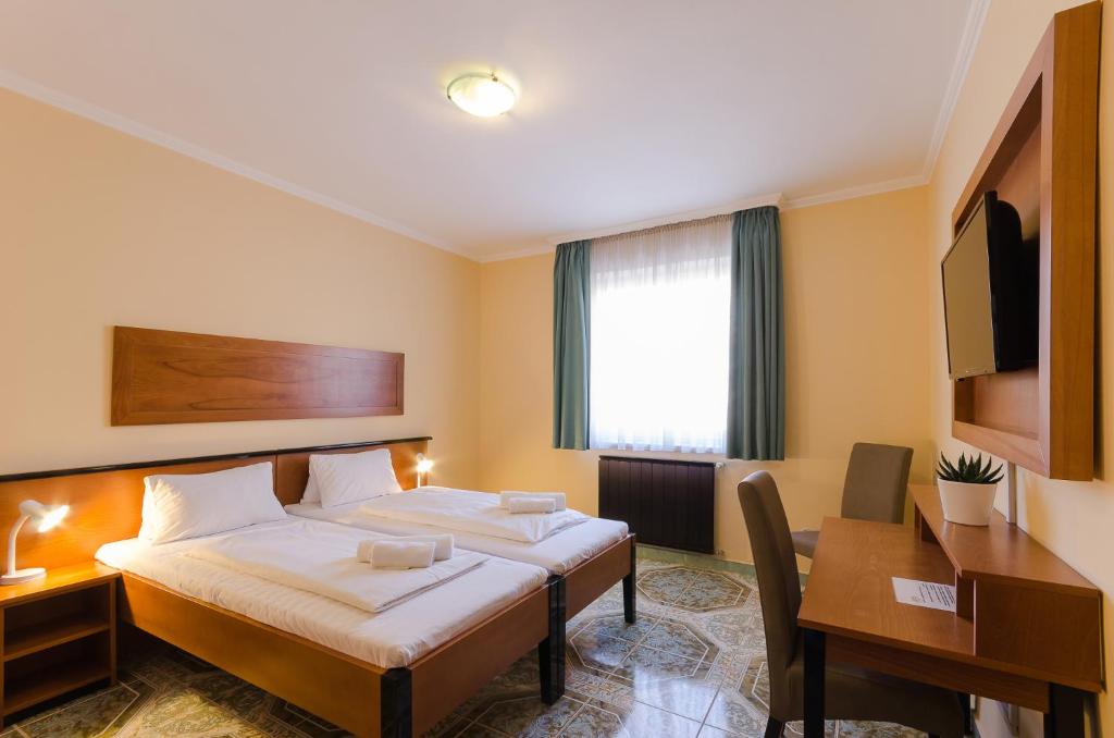 ブダペストにあるRichter Pansionのベッドとデスクが備わるホテルルームです。