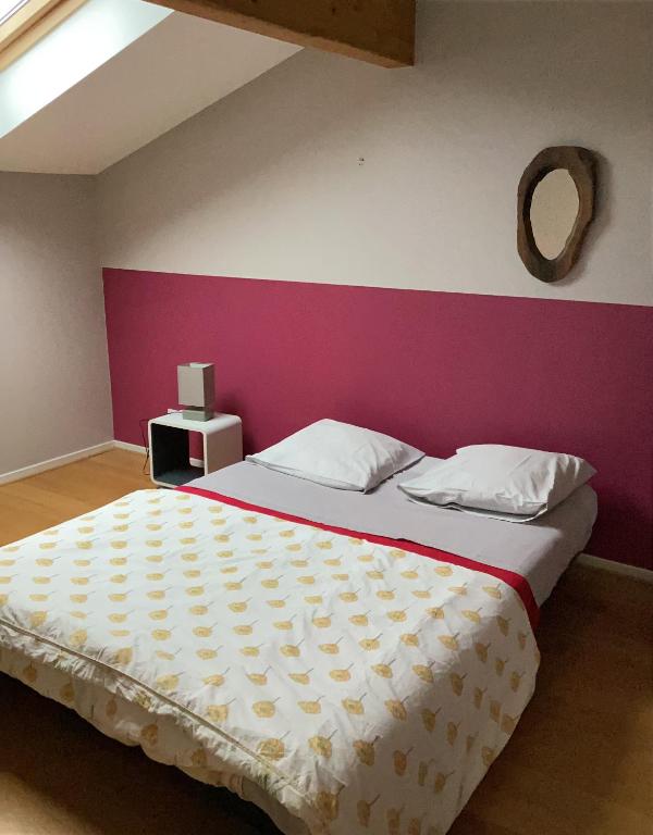 - une chambre avec un grand lit et un mur rose dans l'établissement Le chardon lorrain, à Nancy
